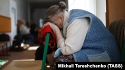 A woman rests her head at a temporary accommodation center for evacuated residents in Volodarskoye, 25 kilometers from the city of Mariupol in Russian-occupied Ukraine, in March 2022. 