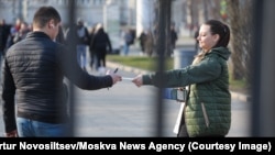 A woman in Moscow hands out leaflets calling on people to join the Russian Army.