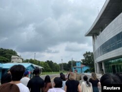 Рядовой США Трэвис Т. Кинг (в черной рубашке и черной кепке) виден на этом снимке, сделанном во время тура по жестко контролируемой совместной зоне безопасности (JSA) на границе между двумя Кореями, в деревне перемирия Пханмунджом, Юг. Корея, 18 июля 2023 года.