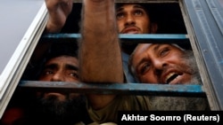 Afghan nationals, who, according to police, were undocumented, spoke to the members of the media from the window of a bus as they were detained in Karachi, Pakistan, on November 2.