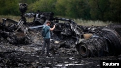 A journalist takes photographs at the site of the Malaysia Airlines Boeing 777 plane crash near the settlement of Hrabovo, in the Donetsk region, on July 18, one day after the crash, which killed all 298 people aboard.