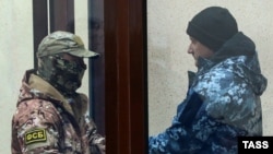 Наглядач ФСБ (л) і один із військовополонених моряків (п) в окупованому Криму, фото 28 листопада 2018 року