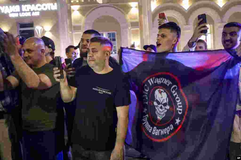People cheer and wave a Wagner flag near the military headquarters in Rostov-on-Don. The Kremlin said Belarusian strongman Alyaksandr Lukashenka helped mediate the deal. Kremlin spokesman Dmitry Peskov said Putin and Lukashenka had guaranteed Prigozhin's safety. 