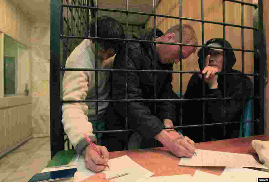 Illegal migrants from the former Soviet republics fill out forms as they wait in a holding cell at a police station in Krasnoyarsk in September 2013. 