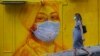 HONG KONG -- A pregnant woman wearing a face mask as a precautionary measure walks past a street mural in Hong Kong, on March 23, 2020