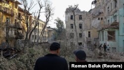 Сотрудники украинской ГСЧС стоят рядом с жилыми домами, поврежденными в результате российского удара по Львову, 4 сентября 2024 года