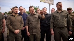 Ukrainian President Volodymyr Zelenskiy (left) thanked rescuers on June 8 as he visited a crossing point for those evacuated from flooded areas in the southern region of Kherson. 
