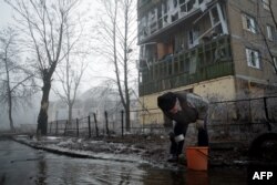 Донеччанин черпає воду з пошкодженого водогону, лютий 2015 року