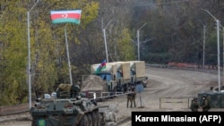 NAGORNO-KARABAKH -- Russian APC and soldiers of the peacekeeping force (L) patrol in front of an Azerbaijan's army checkpoint near the demarcation line outside the town of Shushi (Susa), November 26, 2020