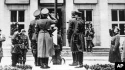 Військовослужбовці нацистської Німеччини і СРСР віддають честь німецькому прапорові зі свастикою під час урочистостей у рамках військового параду з нагоди поділу земель, що належали до того Польщі. Брест-Литовський, 22 вересня 1939 року