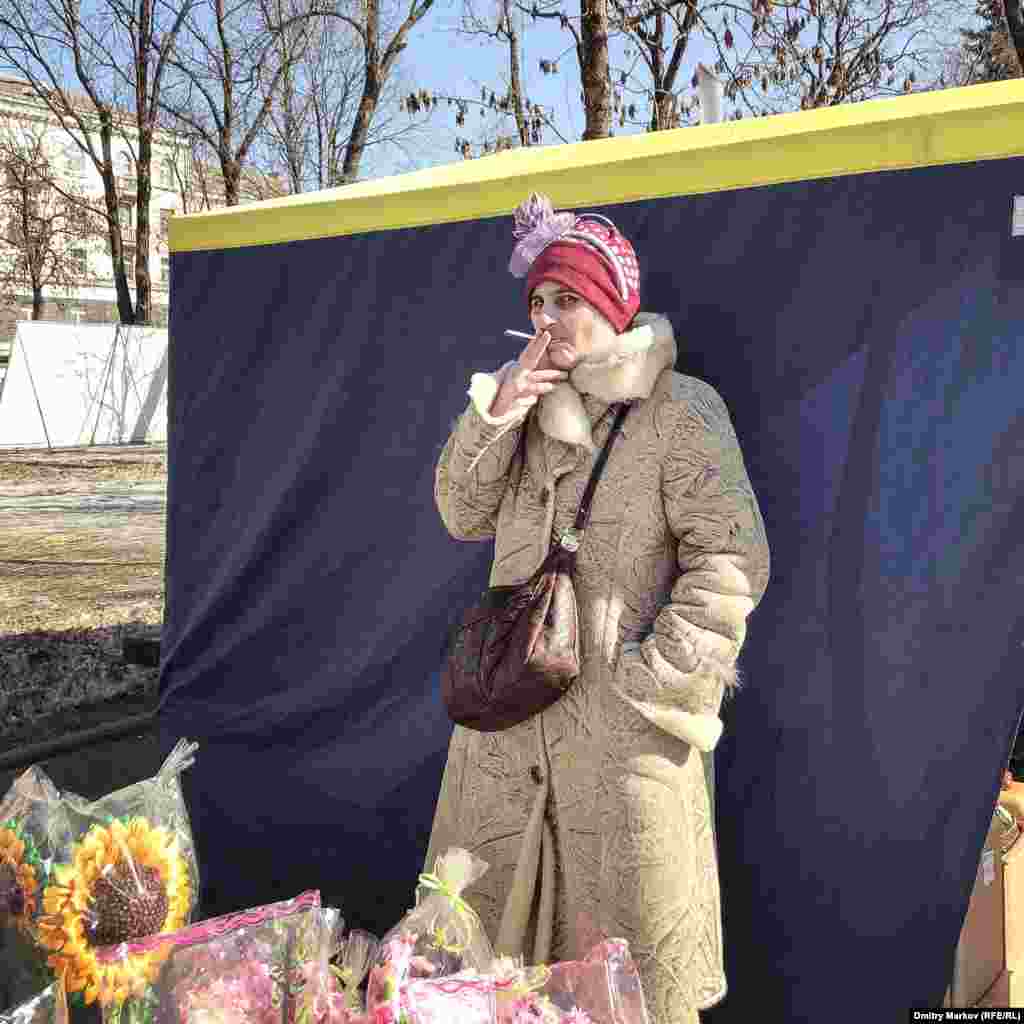A woman sneaks a puff of her cigarette while watching over her souvenir stall. 