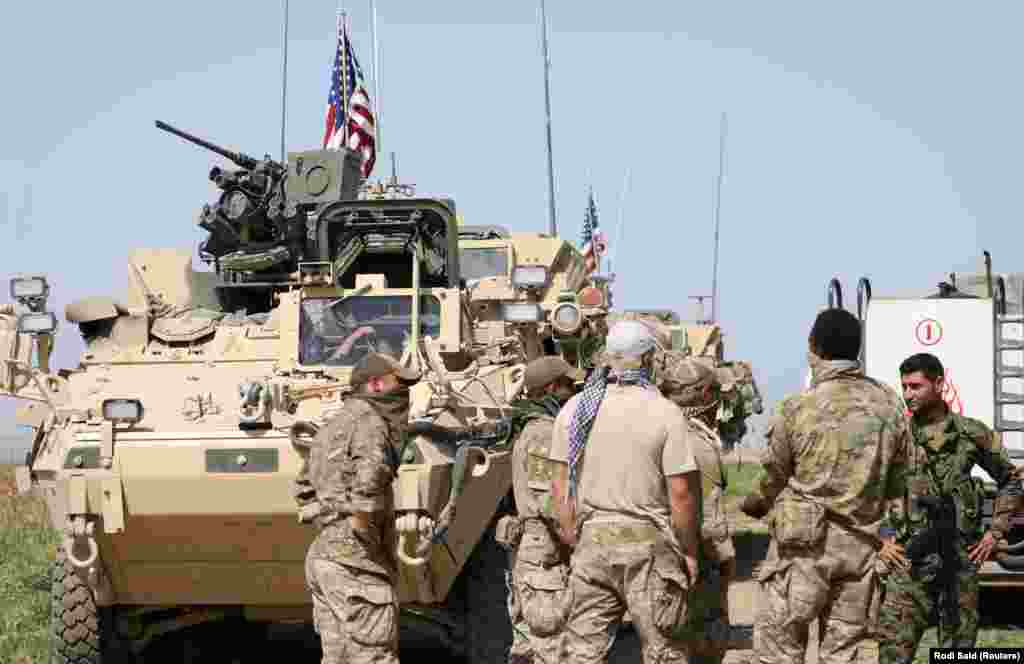 Kurdish fighters from the People's Protection Units (YPG) chat with members of U.S. forces in the Syrian town of Al-Darbasiyah in April 2017. The stated U.S. mission in Syria includes training and advising rebel forces fighting Islamic State (IS) militants. 