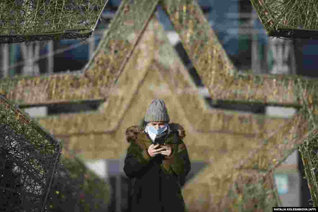 A woman wearing a face mask walks through star-shaped decorations in Moscow.