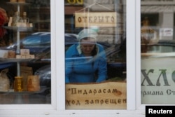 An employee arranges products on display next to a sign saying "No pederasts allowed" at a Bread And Salt store in central Moscow.