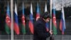 Озарбайжон ва Россия байроқлари олдидан ўтиб кетаётган шахс. Расм иллютрация учун ишлатилди. 