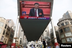 A giant screen shows Chinese President Xi Jinping attending the closing session of the National People's Congress at the Great Hall of the People in Beijing on March 11.