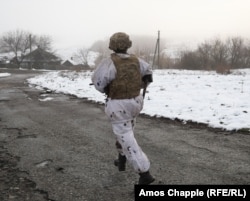 Український військовослужбовець біжить, оглядаючи сусідні позиції російських гібридних сил у Луганській області, 7 грудня 2021 року