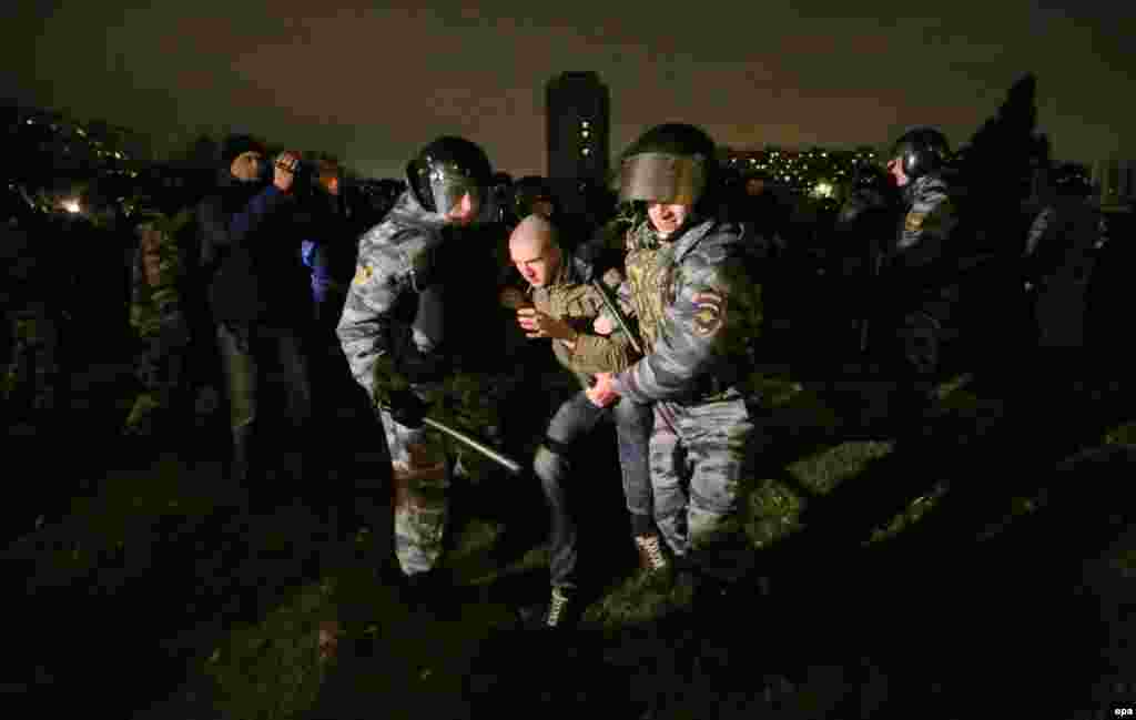 Russian policemen detain a protester near the Biryuza shopping mall in Moscow in October 2013 during massive riots sparked by claims a labor migrant had killed a local Russian. The incident sparked some of the worst violence in the capital in years, with nationalists overturning cars, smashing windows, and storming a vegetable warehouse looking for migrants.
