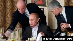 Businessman Yevgeny Prigozhin (left) serves food to then-Russian Prime Minister Vladimir Putin in 2011.