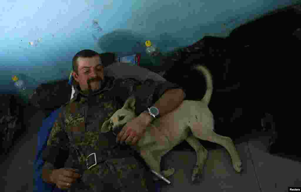 A Ukrainian serviceman rests with a dog at a military camp near the town of Horlivka in eastern Ukraine in September 2014.
